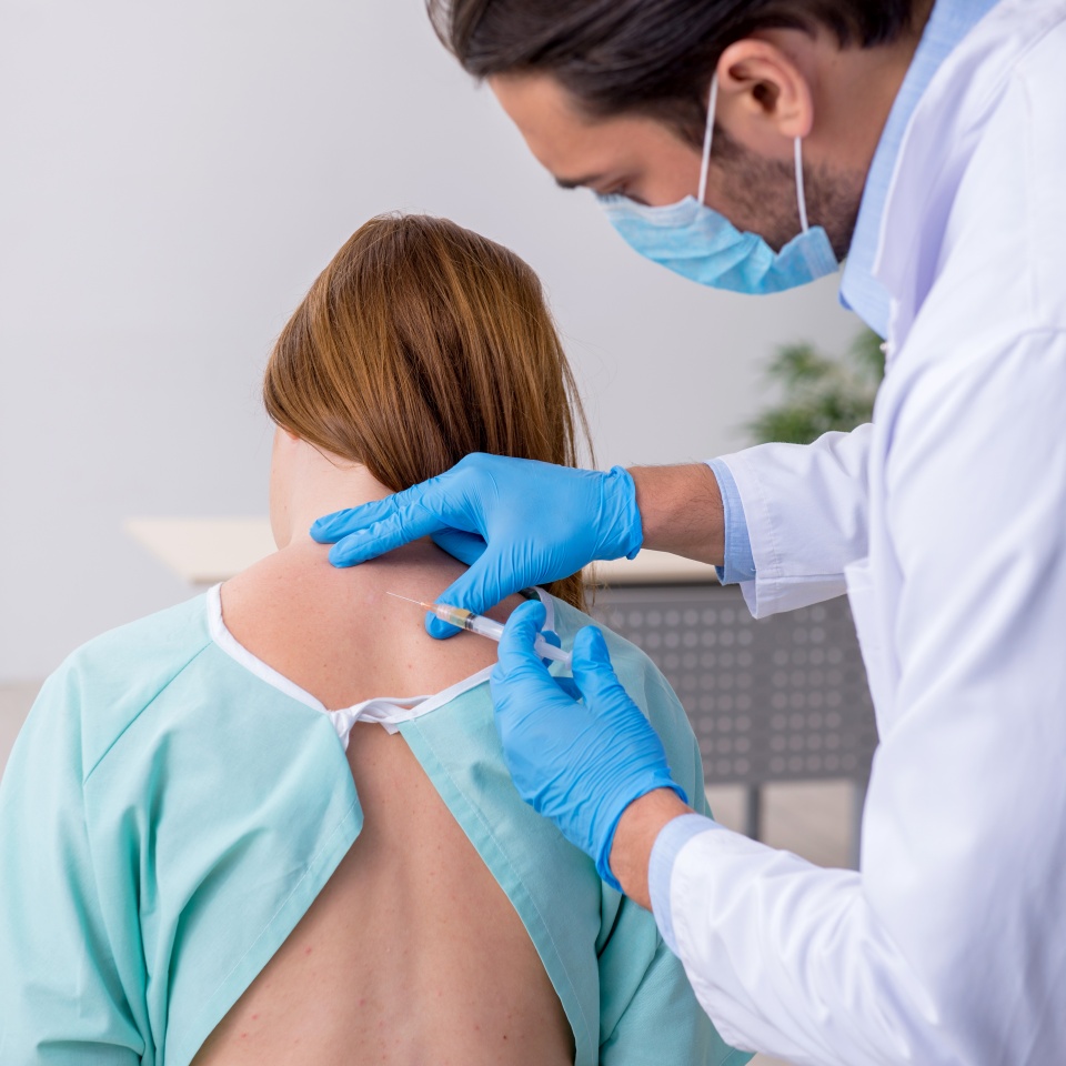 Young injured woman visiting male doctor chiropractor