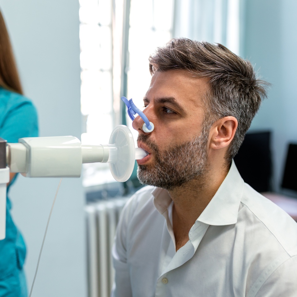 Medical Professional Conducting Spirometry Test for male Patient. Respiratory Therapist Monitoring Lung Function Results. Healthcare Specialist Performing Pulmonary Assessment in Hospital.