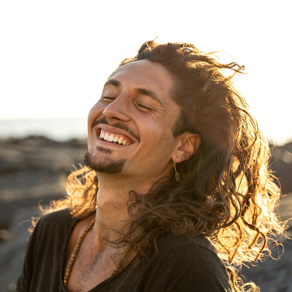Portrait of happy handsome hippie italian man with long hair smiling beautiful . Freedom. Wanderlust. Tropics. Traveler.Beach. Relax. Tourism.