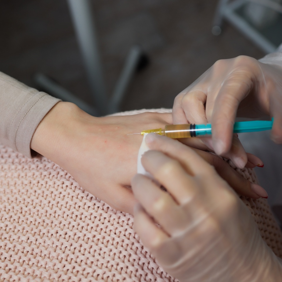 Doctor doing stem cell therapy on a patient's elbow after the injury. Treating knee pain with platelet-rich plasma injection. Treatment of arthritis and osteoarthritis.Medical and cosmetology concept