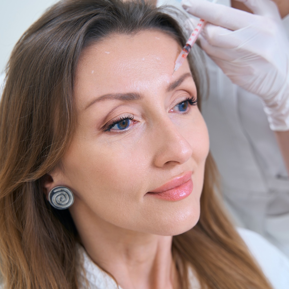 Pretty woman on the procedure at the doctor for forehead skin rejuvenation with mesotherapy injections