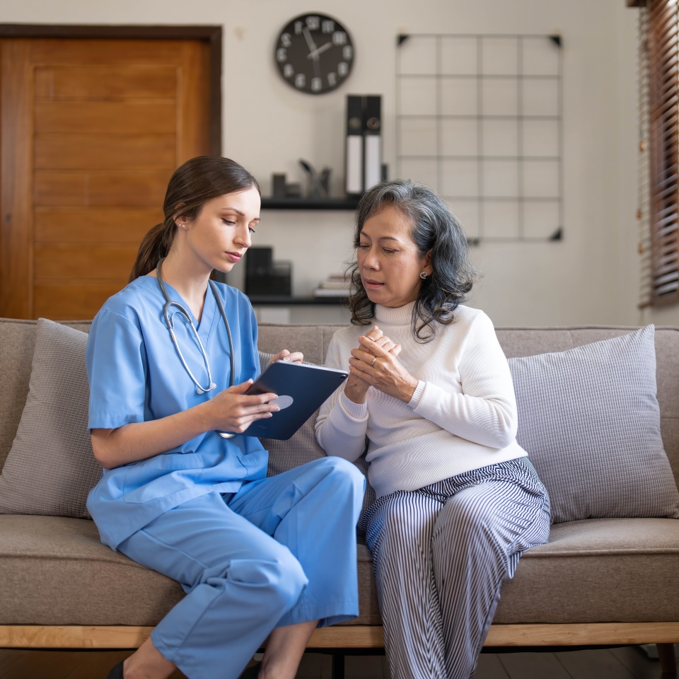 Asian nurse showing health checkup report to grandmather and giving advice. medical assisted living visit senior patient at home. Home nursing and healthcare caregiver concept